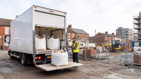 A 7.5T lorry unloading building materials at a construction site in North London, UK
